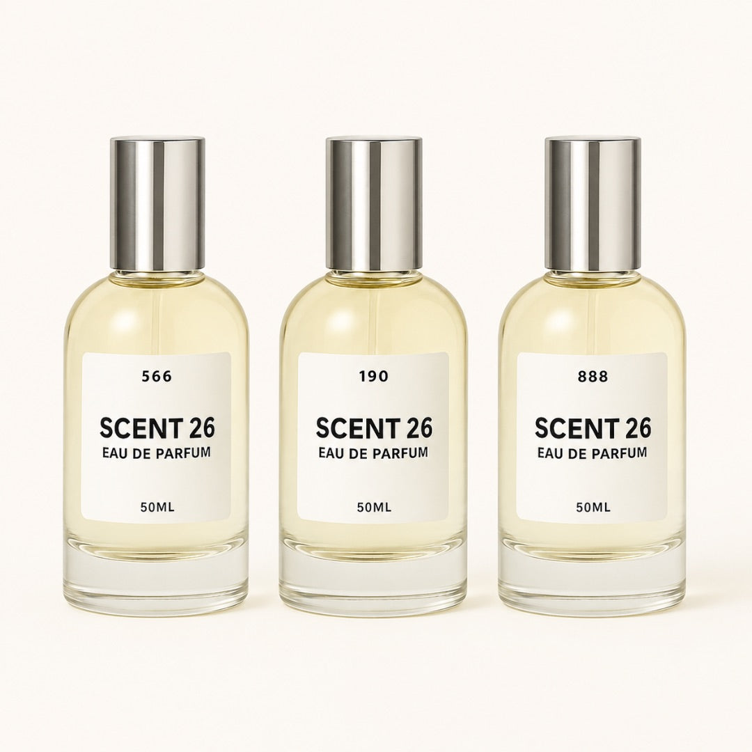Three identical 50ml bottles of Scent 26 Eau De Parfum arranged side by side on a clean off-white background. Each bottle has a clear glass body filled with pale yellow liquid, a white label with black text, and a reflective silver cap.