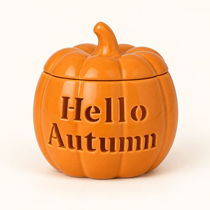 An orange pumpkin-shaped ceramic jar with a lid, featuring the embossed text 'Hello Autumn' on the front, set against a plain white background.