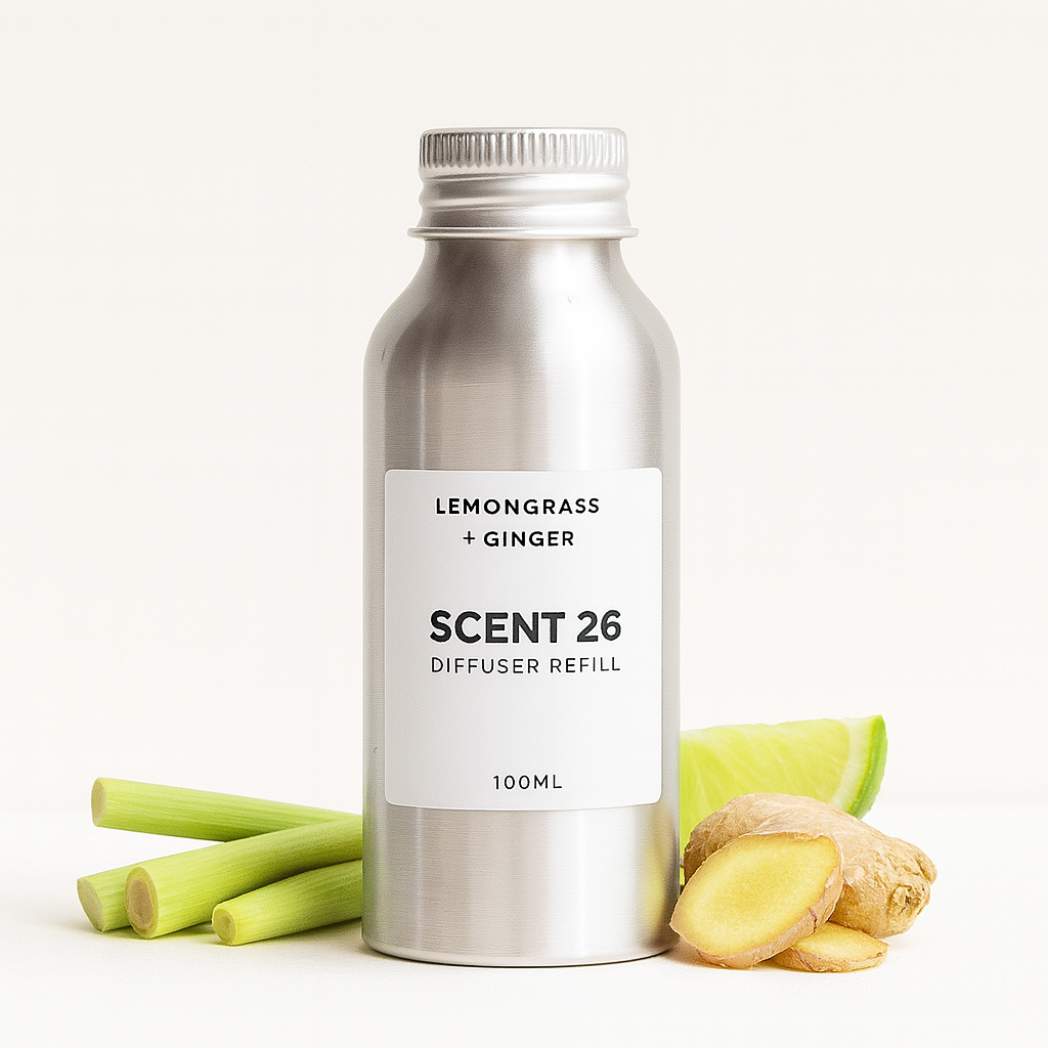 Scent 26 Lemongrass + Ginger diffuser refill 100ml bottle with lemongrass stalks, ginger slices and lime wedge props, evoking a zesty, refreshing citrus and spa-like scent.